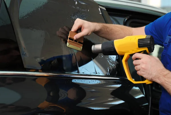 Technician using heat gun to apply window tint